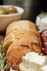 Cheese, vegetables, fruits and spices. Bread, olives and crackers. Mediterranean diet and cuisine. Dark background.