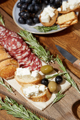 Cheese, vegetables, fruits and spices. Bread, olives and crackers. Mediterranean diet and cuisine. Dark background. Top view.