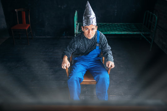 Scared man in aluminum foil hat sits in chair