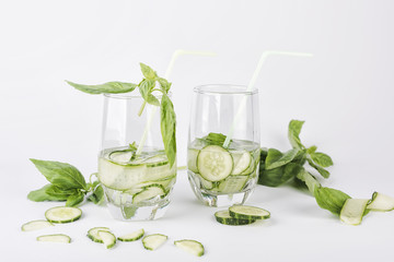 Glasses of cucumber detox water. Homemade cold gin tonic with basil isolated on the white background