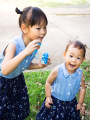 Two Asian girl  blowing bubbles. Funny activity. Little girl smiling and oldest girl blow.