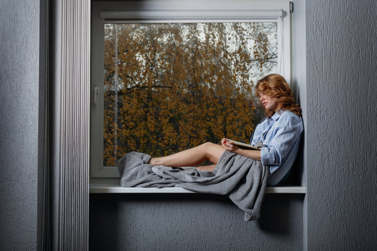 Young attractive girl on the window sill .