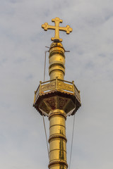 Fototapeta na wymiar Narrow close up view of gold colored pillar with a cross at top