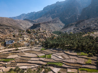 Aerial drone view of an old traditional Omani mud village in the mountains among date palm trees. Balad Seet, Oman.
