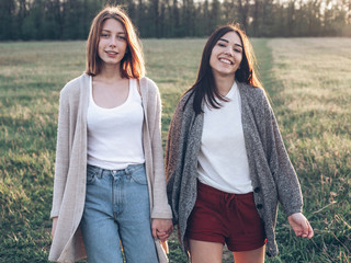 Two young women walking outdoors at sunset. Best friends