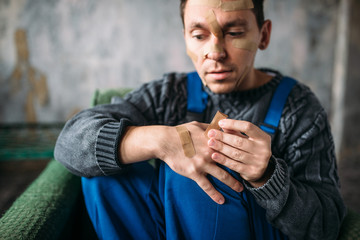 Madman in uniform with plasters on face and hands