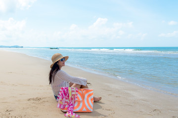 Freedom lifestyle asian woman sitting on the beach looking at the sea and sky.  Travel and Summer Concept.