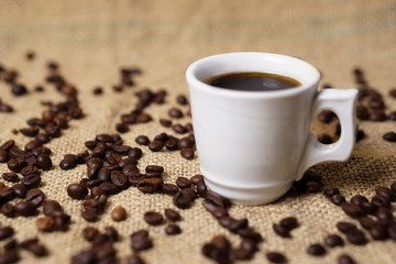 Cup of coffee on sackcloth with coffee beans