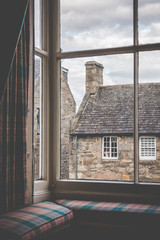 Tartan curtains and cushions on a window seat in an old country scottish village. shot from indoors looking out towards these old georgian buildings