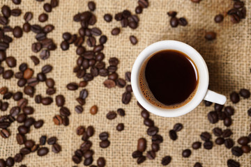 Cup of coffee on sackcloth with coffee beans
