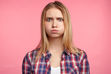 Studio portrait of upset offended abused blonde female blows cheeks in dissatisfaction, finds out...
