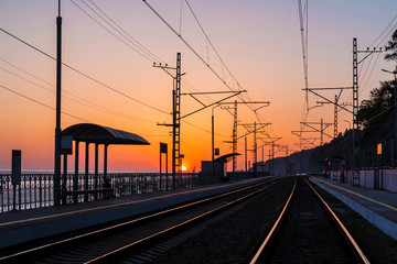 Fototapeta na wymiar The platform of the railway station and the railroad going into the distance at sunset, Sochi, Russia
