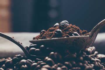 Coffee poured into an ancient antique silverware spoon. Around the spoons scattered coffee beans.