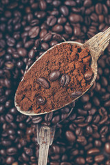 Coffee poured into an ancient antique silverware spoon. Around the spoons scattered coffee beans.