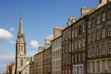 Fototapeta na wymiar Looking up at a row of houses and church steeple in an Edinburgh (Scotland) street on a beautiful sunny day