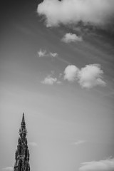 looking up towards the scott monument in Edinburgh on a cloudy day in black and white with dramatic clouds