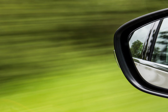 Car wing mirror abstract zooming past grass road