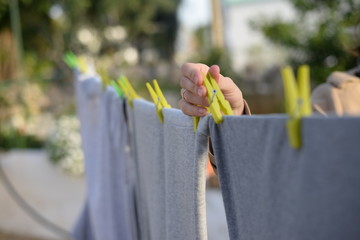 Clothes hanging on sunny light outdoors landscape background, close up photography on woman hand.