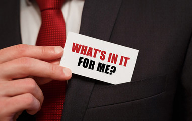 Businessman putting a card with text WHATS IN IT FOR ME in the pocket