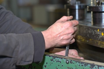 metalworking industry: factory man worker in uniform working on lathe machine in workshop