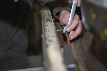 metalworking industry: factory man worker in uniform working on lathe machine in workshop