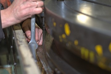 metalworking industry: factory man worker in uniform working on lathe machine in workshop