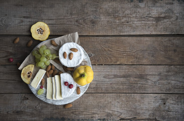 camembert cheese, fruits and nuts on the wooden table 