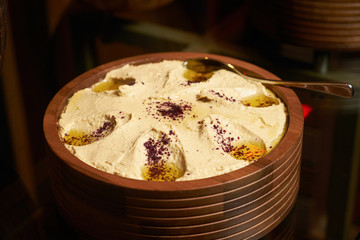 Cream sauce with barberry seasoning and olive oil in a wooden bowl
