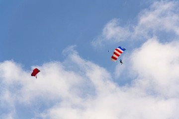 Two parachutists skydiving with colorful parachute clouds blue sky background