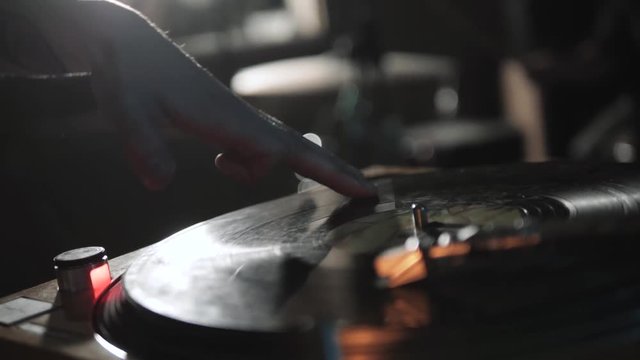 Disc jockey scratch vinyl record with music on turntable records player. Turntables vinyl disc in focus. Play music on dj audio equipment in night club. Close up,focus on djs hand on disc. Turntables