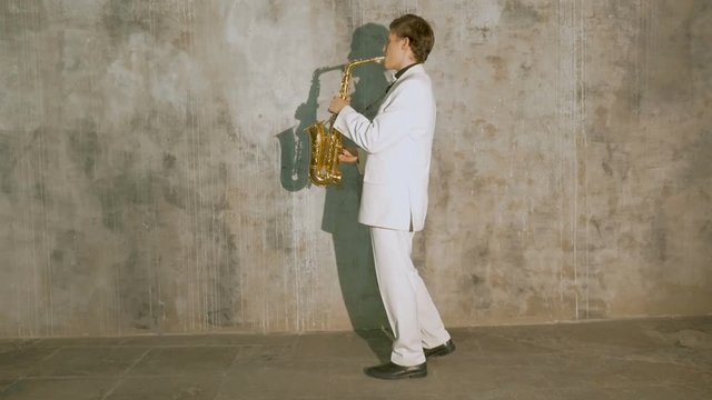 A musician in a white suit plays the saxophone.