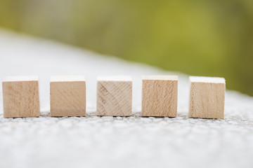 Plain wooden cube on book.  selective focus on wooden cube block on green notebook 