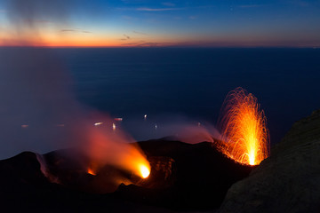 Lava fountain on the summit of the erupting volcano Stromboli, Italy, at sunset.