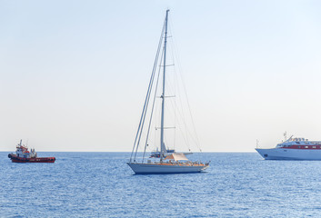 One fancy boat docked at sea and three boat passing by with clean blue sky