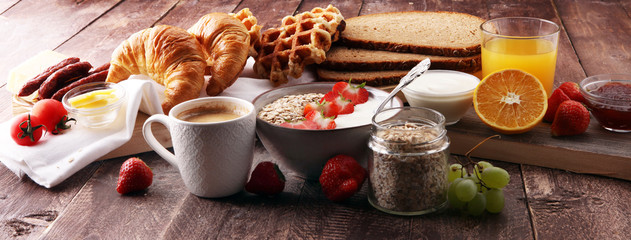 Fototapeta na wymiar Breakfast served with coffee, orange juice, croissants, cereals and fruits. Balanced diet