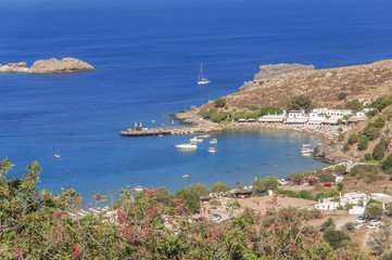 Naklejka na ściany i meble Panoramic view of small sandy beach in Lindos town at island Rhodes on sunny day