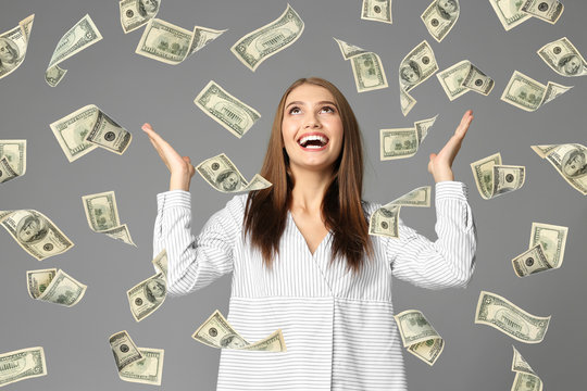 Young woman with money on grey background