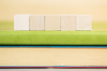 Plain wooden cube on book.  selective focus on wooden cube block on green notebook 