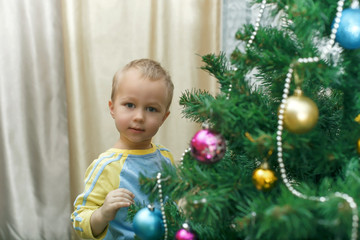 Fototapeta na wymiar little boy hanging decorations for Christmas spruce