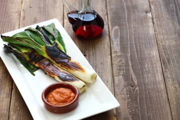 roasted calcots with romesco sauce for dipping, spanish catalan cuisine isolated on white background