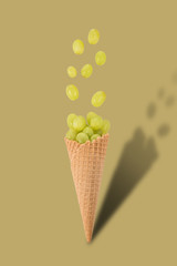 Ice cream cone with grape on bright background. Fruit and candy concept.