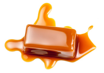 Caramel sauce flowing on caramel candies, isolated on white background. Golden Butterscotch toffee...