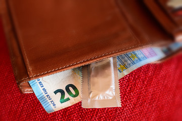 Condoms and banknotes in the leather wallet