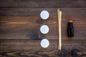 Skin care and relax. Cosmetics and aromatherapy concept. Oil and candles on dark wooden background top view copyspace