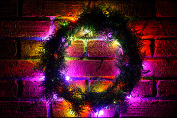 Wreath and garlands of colored light bulbs.Christmas background with lights and free text space. Christmas lights border. Glowing colorful Christmas lights on a brick wall background. New Year.  
