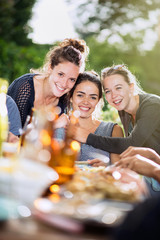  young women lunching on a terrace with friends pose for a photo