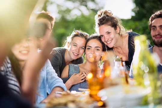  young women lunching on a terrace with friends pose for a photo