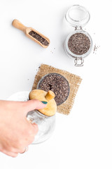 Hand brew chia seeds. Jar with seeds, scoop, bowl, tea pot with hot water. White background top view
