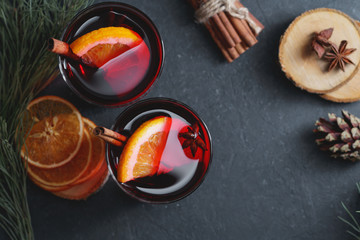 Top view of sweet mulled wine for two person in glasses on the festive table,. decorated spices, dried orange slices and pine branches. The concept of Christmas and New Year.