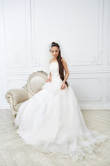 Slim beautiful young woman posing in a wedding dress in studio